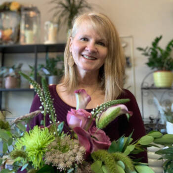 A picture of lee Dorsey the owner and designer at In Bloom holding a flower bouquet