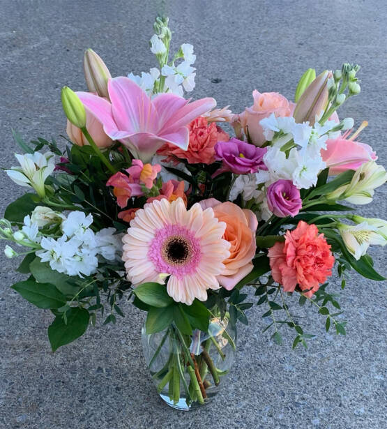 a pink and white floral arrangement in a vase