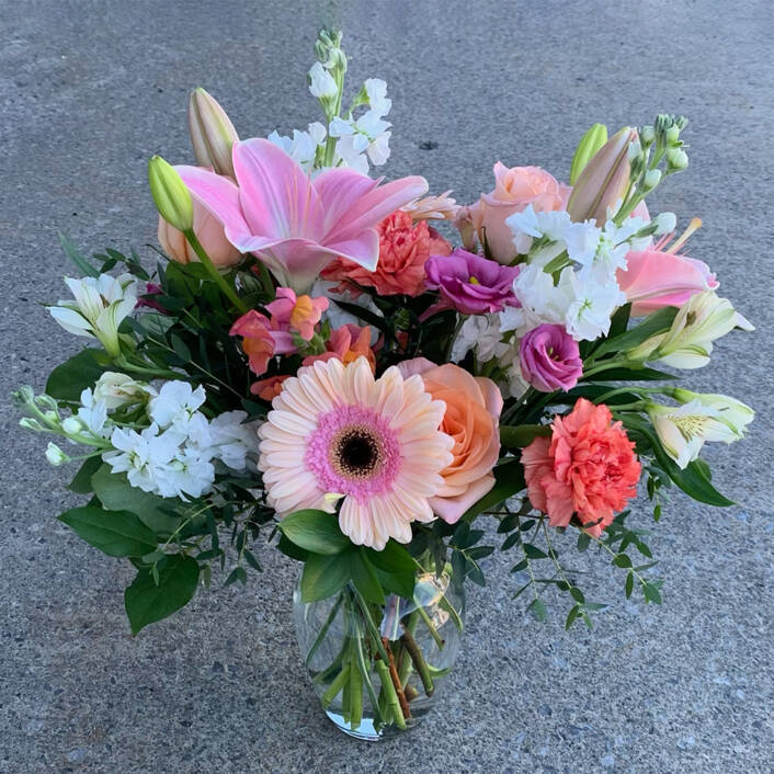 a pink and white floral arrangement in a vase