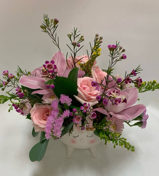 a pink floral arrangement in a potted vase in the shape of a bunny