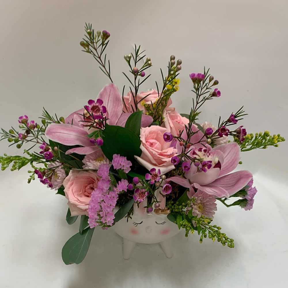 a pink floral arrangement in a potted vase in the shape of a bunny