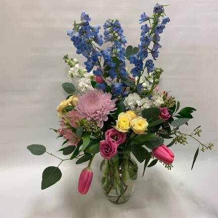 a spring floaral arrangement with blue, pink and yellow flowers in a vase