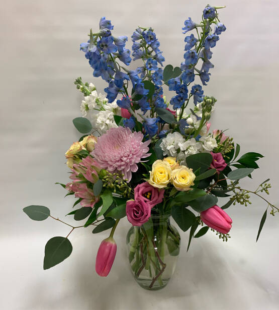a spring floaral arrangement with blue, pink and yellow flowers in a vase