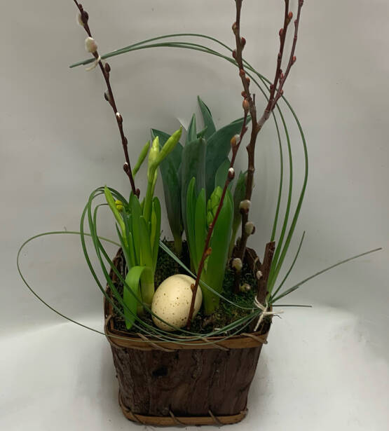a green easter arrangement with an egg in a wood basket