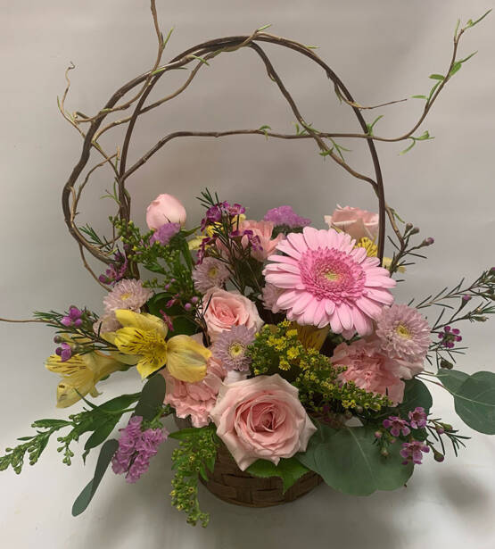 a pink and yellow spring floral arrangement in a basket