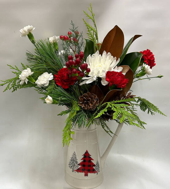 A red and White Christmas arrangement inside a white ceramic Christmas pitcher