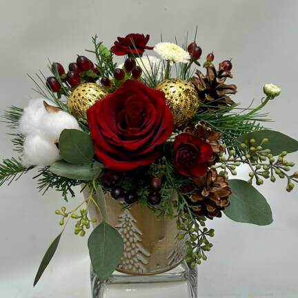 A red, green, white a gold Christmas arrangement with pinecone in a gold metal Christmas pot