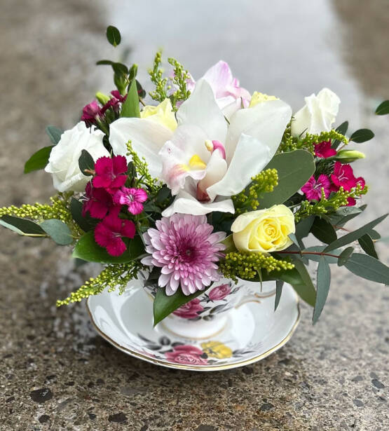A colourful spring themed arrangement in a oval glass vase