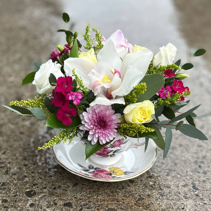 A colourful spring themed arrangement in a oval glass vase