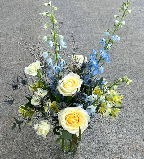 A blue and white floral arrangement in a glass vase