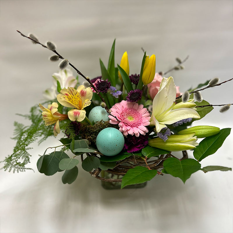 A colourful spring themed arrangement with two baby blue robins eggs